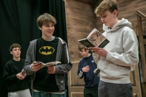 Two young male actors rehearse with scripts in hand