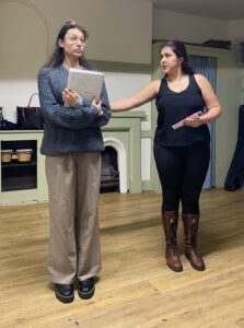 Two female actors stand talking