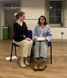 Two female actors sit talking